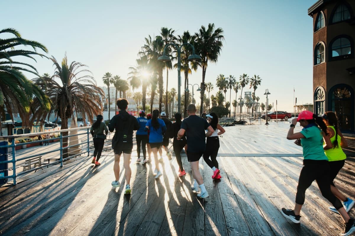 Grupo de corrida treinando junto em um calçadão à beira-mar